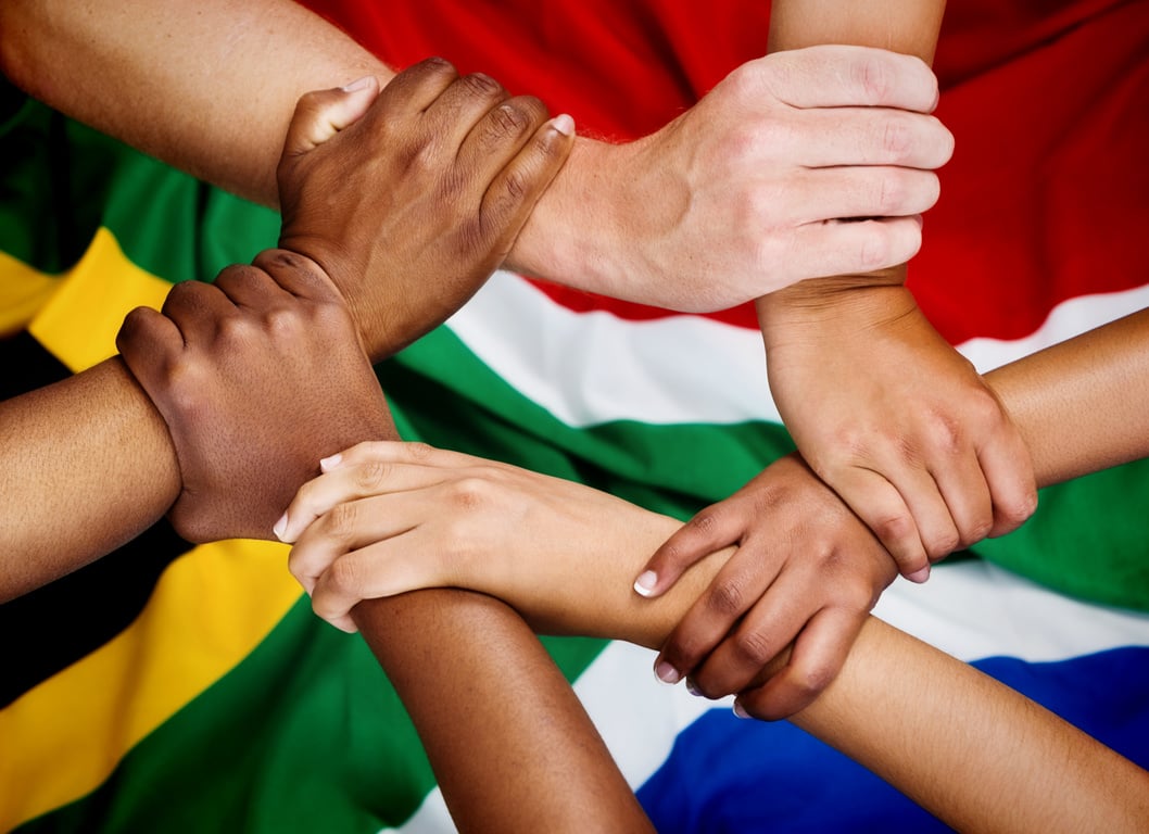 Rainbow Nation hands clasped in unity against South African flag